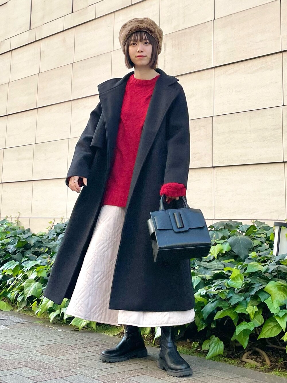 ブラック系のその他アウター、レッド系のニット/セーター、ベージュ系のスカートを着用したレディースの冬コーディネートの4枚目の写真