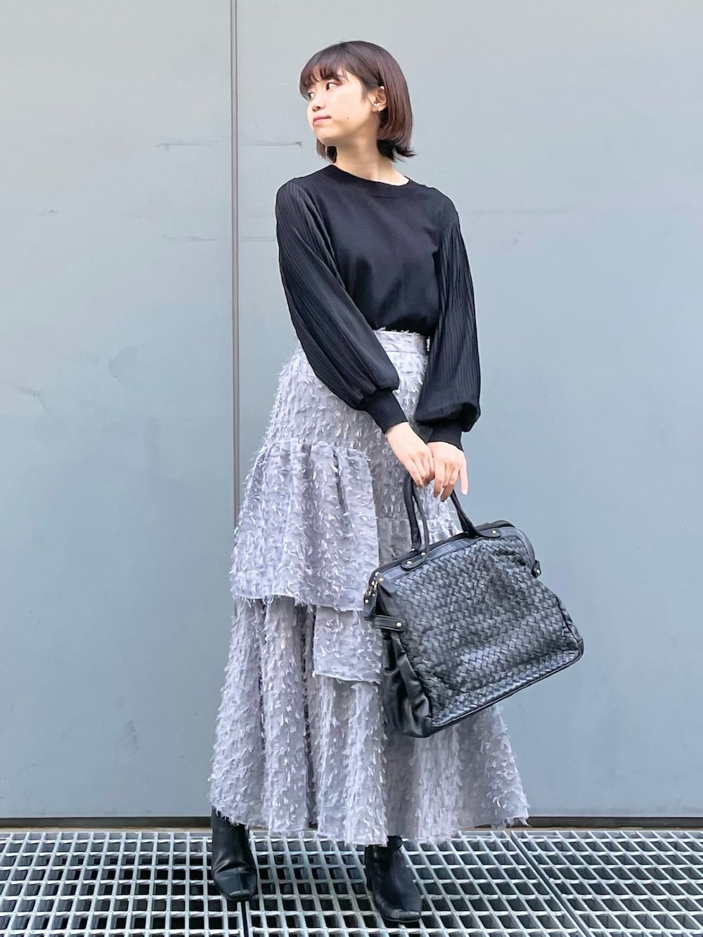 ブラック系のニット/セーター、ブラック系のショルダーバッグ、グレー系のスカートを着用したレディースの秋コーディネートの4枚目の写真