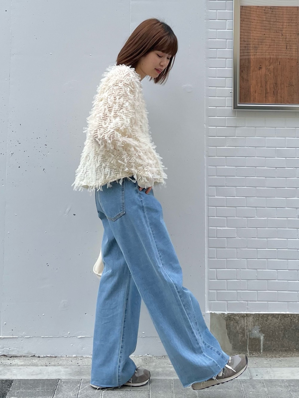 ホワイト系のTシャツ/カットソー、ブルー系のデニムパンツ、グレー系のスニーカーを着用したレディースの冬コーディネートの2枚目の写真