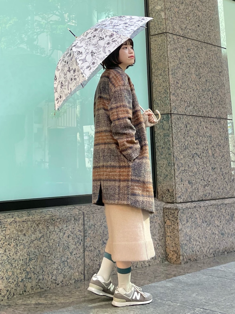 グレー系のスニーカー、オレンジ系のピーコート、ベージュ系のワンピースを着用したレディースの秋コーディネートの3枚目の写真