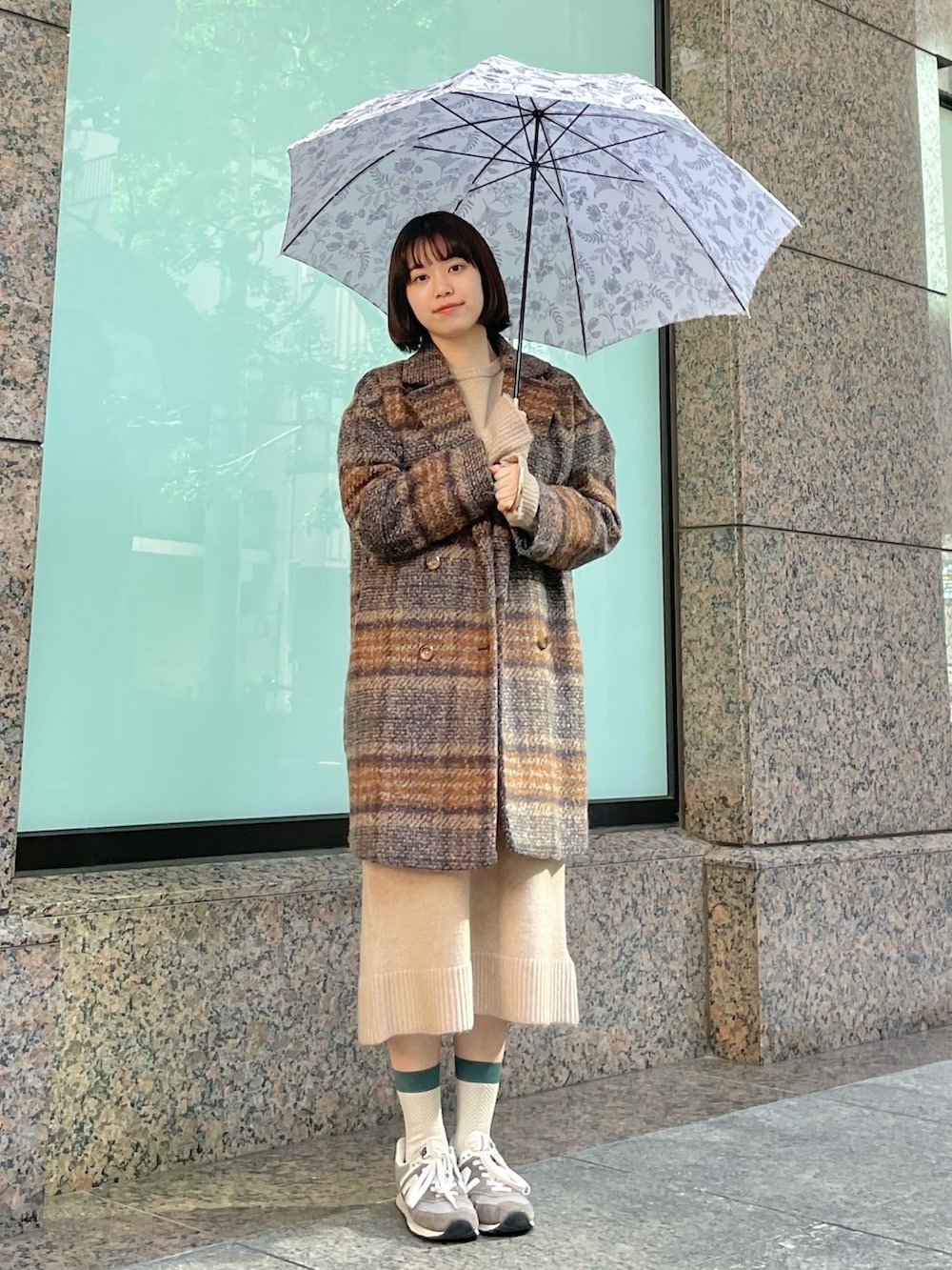 グレー系のスニーカー、オレンジ系のピーコート、ベージュ系のワンピースを着用したレディースの秋コーディネートの2枚目の写真