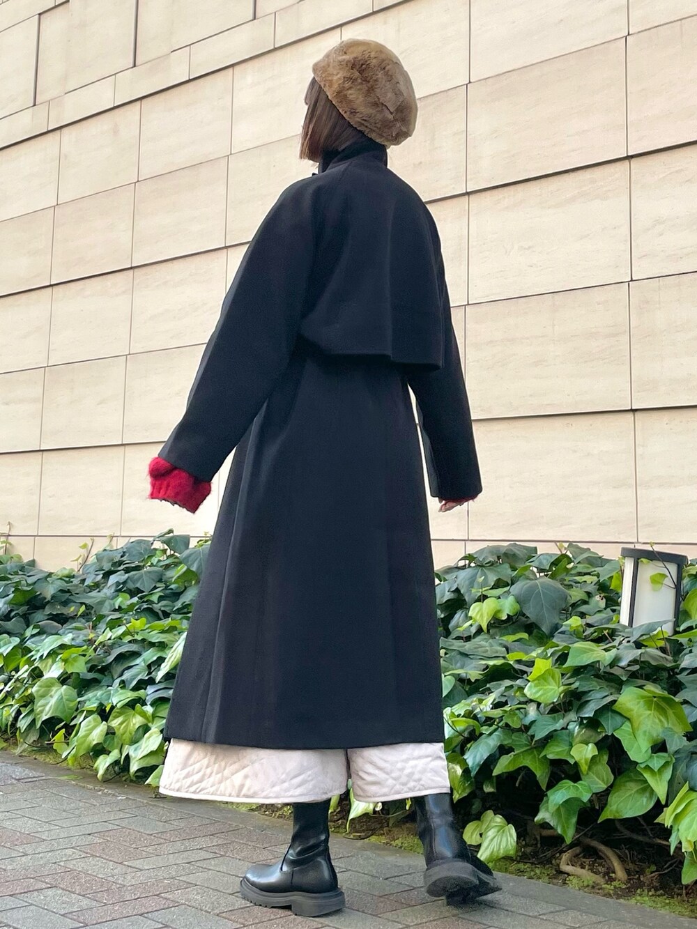 ブラック系のその他アウター、レッド系のニット/セーター、ベージュ系のスカートを着用したレディースの冬コーディネートの2枚目の写真