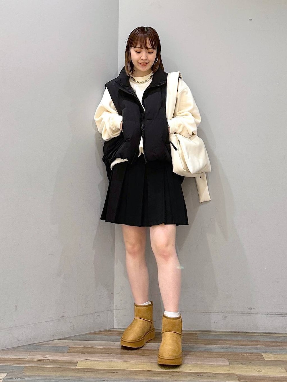 ブラック系のダウンベスト、ホワイト系のスウェット、ホワイト系のショルダーバッグを着用したレディースの秋コーディネートの4枚目の写真