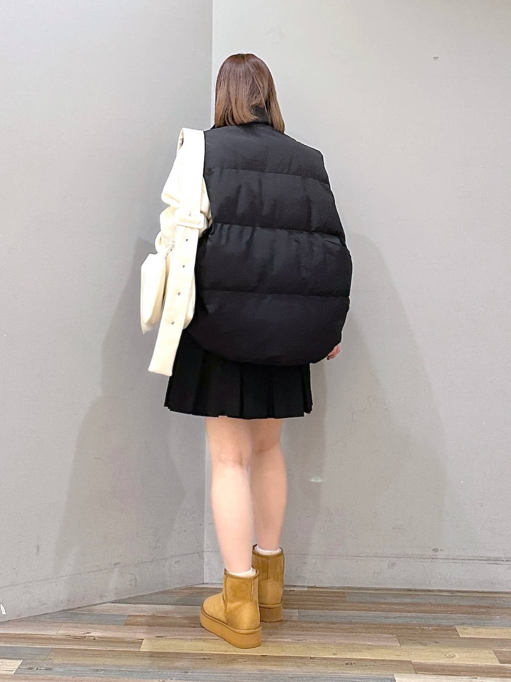 ブラック系のダウンベスト、ホワイト系のスウェット、ホワイト系のショルダーバッグを着用したレディースの秋コーディネートの3枚目の写真