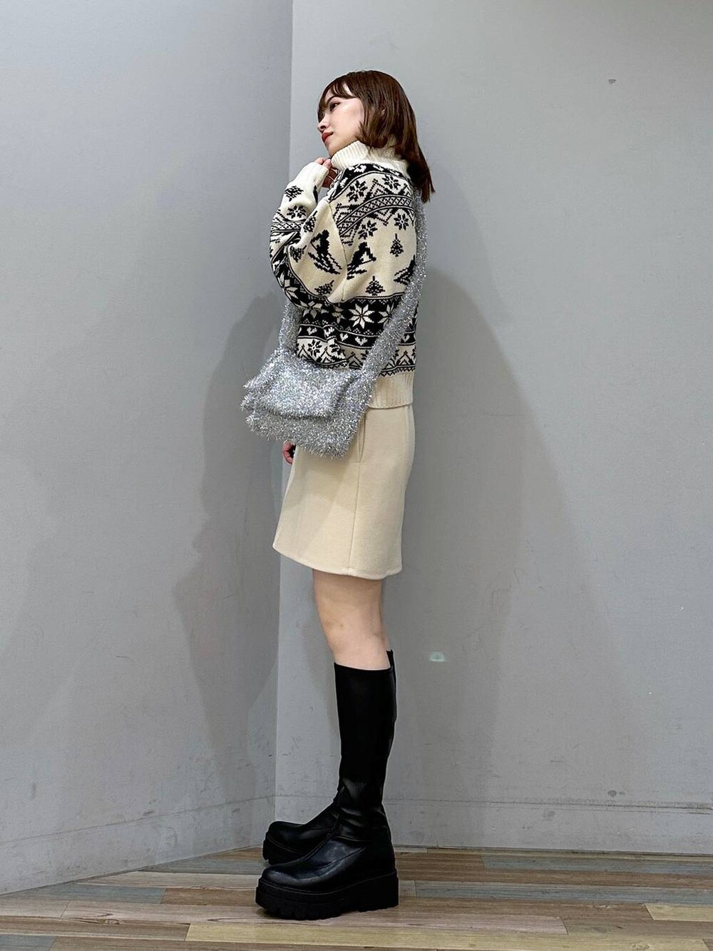 ベージュ系のニット/セーター、ブラック系のブーツ、ホワイト系のスカートを着用したレディースの秋コーディネートの2枚目の写真