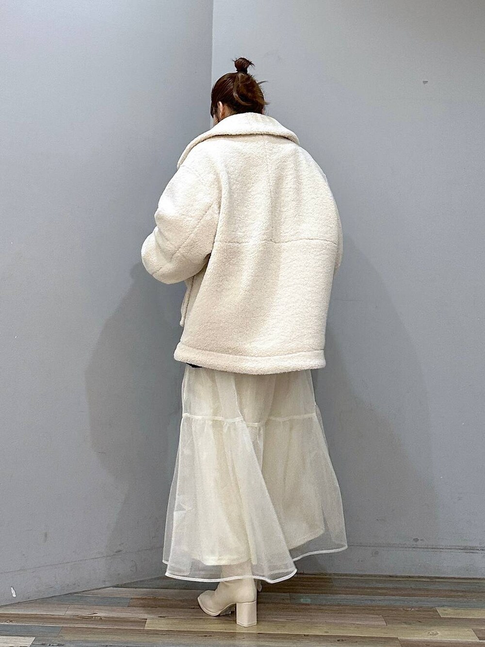 ホワイト系のブルゾン、ホワイト系のパンプス、ホワイト系のスカートを着用したレディースの冬コーディネートの3枚目の写真