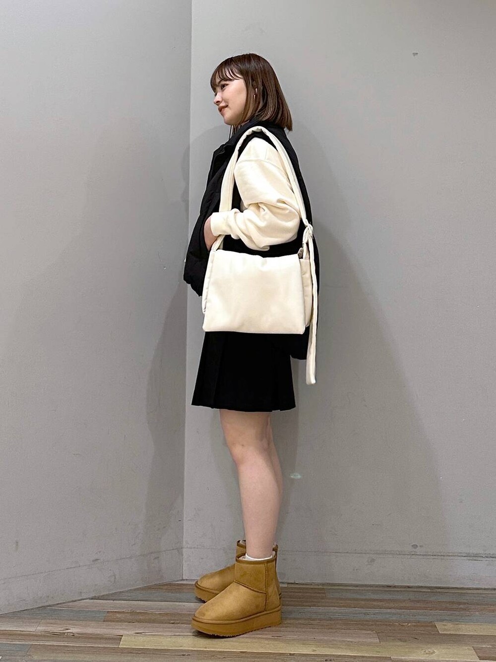 ブラック系のダウンベスト、ホワイト系のスウェット、ホワイト系のショルダーバッグを着用したレディースの秋コーディネートの2枚目の写真