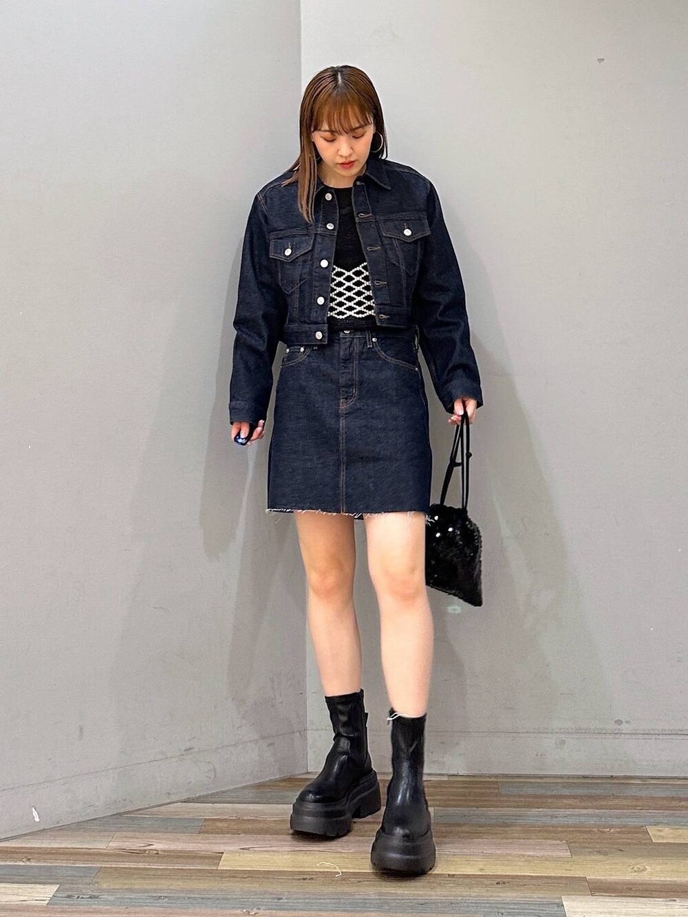 ブラック系のブーツ、ブラック系のハンドバッグ、ブラック系のTシャツ/カットソーを着用したレディースの冬コーディネートの4枚目の写真