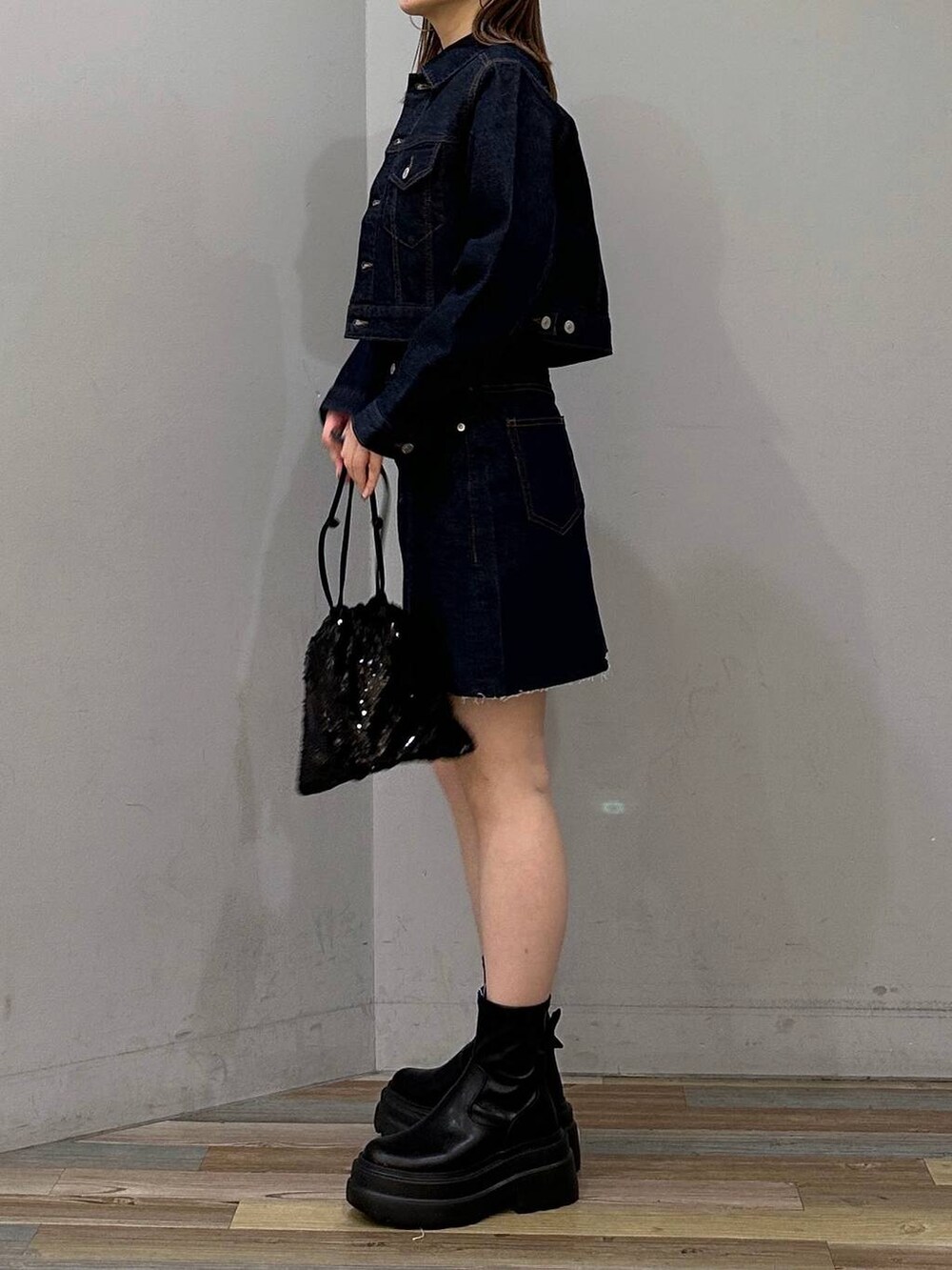 ブラック系のブーツ、ブラック系のハンドバッグ、ブラック系のTシャツ/カットソーを着用したレディースの冬コーディネートの2枚目の写真