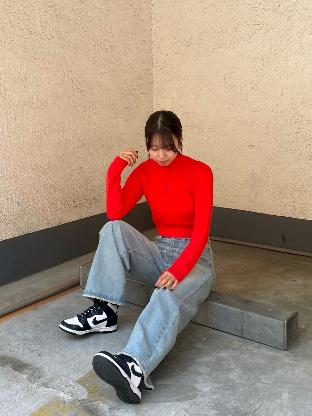 レッド系のニット/セーター、ブルー系のデニムパンツを着用したレディースの秋コーディネートの2枚目の写真