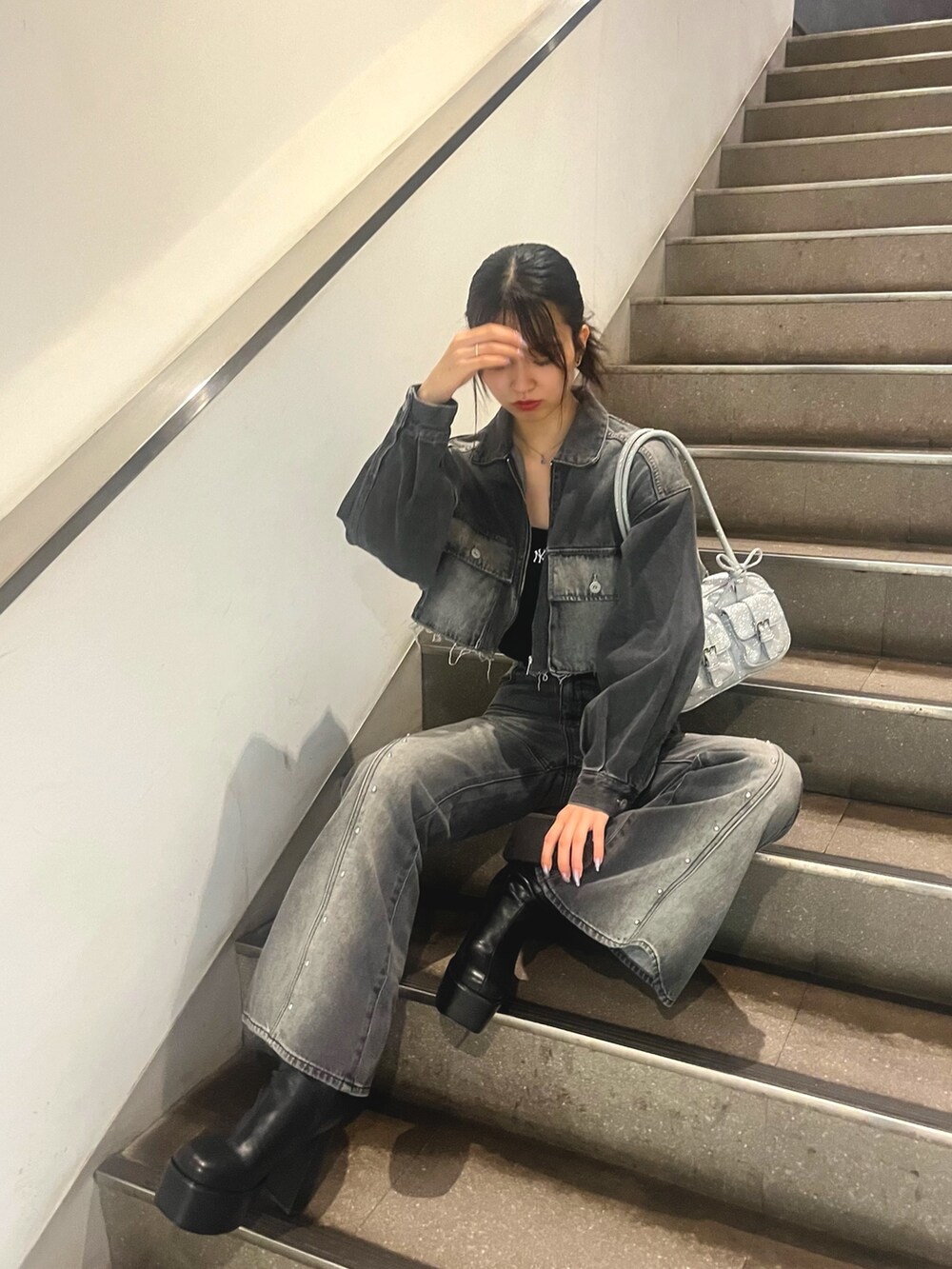 ブラック系のデニムジャケット、ブラック系のデニムパンツ、ブラック系のブーツを着用したレディースの夏コーディネートの2枚目の写真