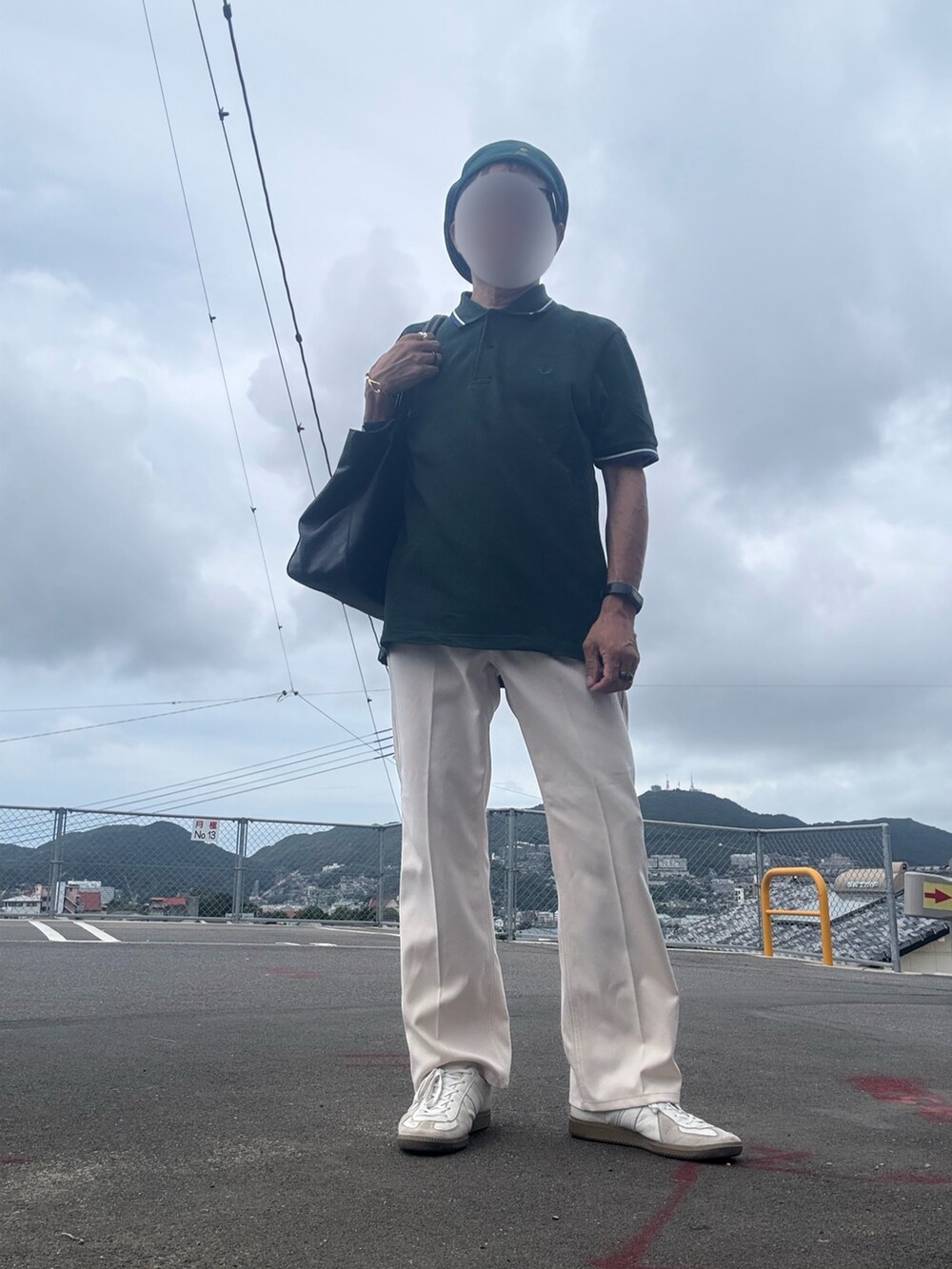 ホワイト系のスラックス、グリーン系のポロシャツ、ホワイト系のスニーカーを着用したメンズの秋コーディネートの2枚目の写真