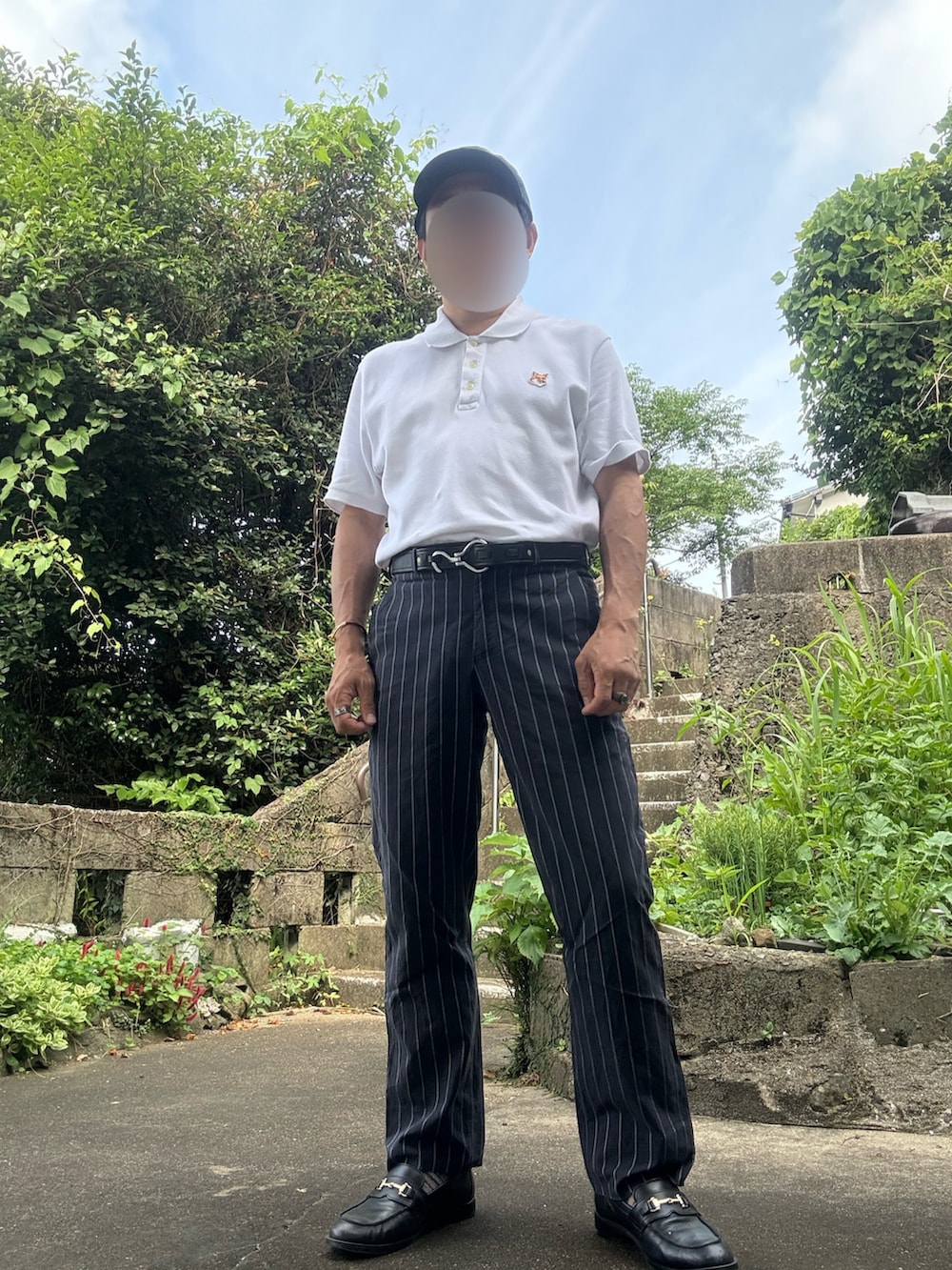 ホワイト系のポロシャツ、ブラック系のスラックス、ブラック系のローファーを着用したメンズの夏コーディネートの2枚目の写真