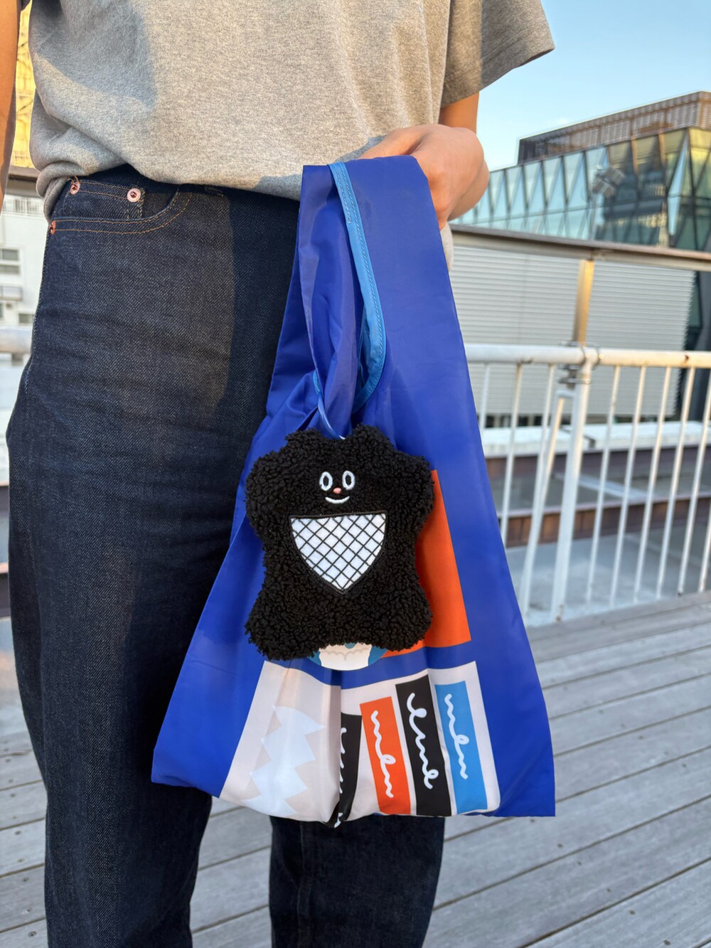 グレー系のTシャツ/カットソー、ブラック系のエコバッグ/サブバッグ、ブルー系のデニムパンツを着用したレディースの冬コーディネートの3枚目の写真