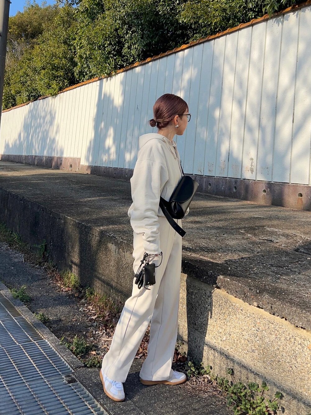 ブラック系のショルダーバッグ、ホワイト系のパーカー、ホワイト系のスラックスを着用したレディースの春コーディネートの2枚目の写真