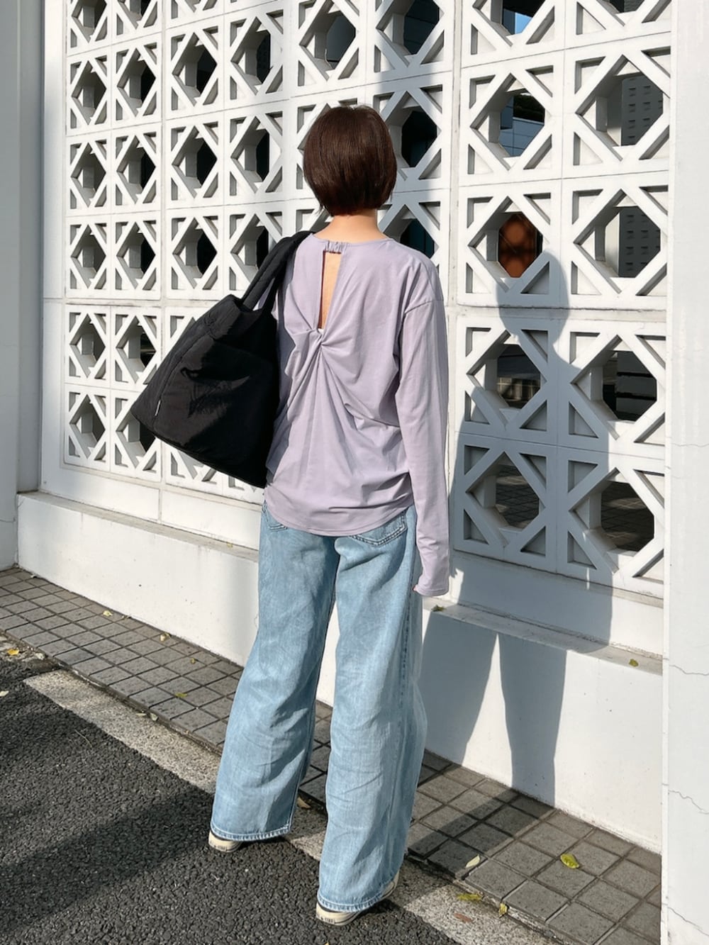 ブラック系のトートバッグ、パープル系のTシャツ/カットソーを着用したレディースの春コーディネートの2枚目の写真