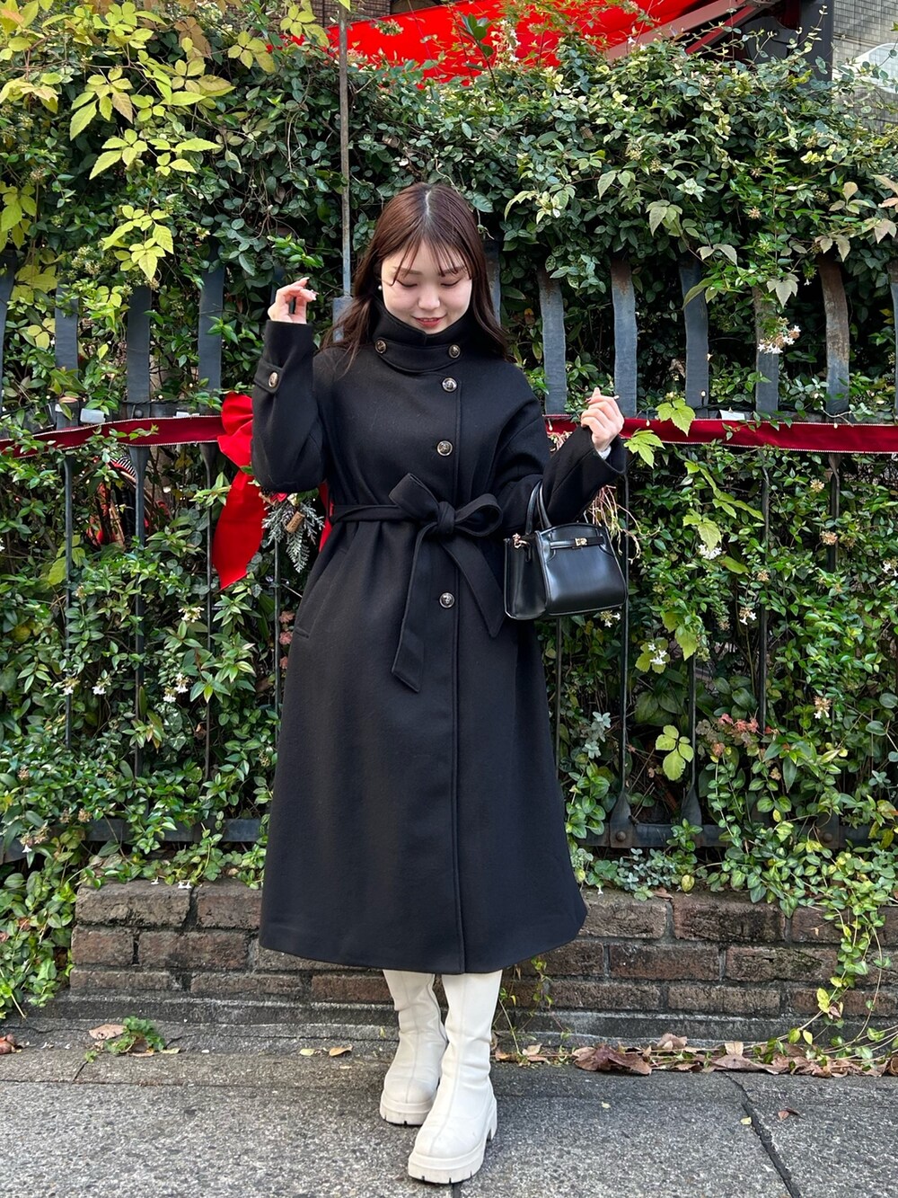 ブラック系のステンカラーコートを着用したレディースの冬コーディネートの2枚目の写真