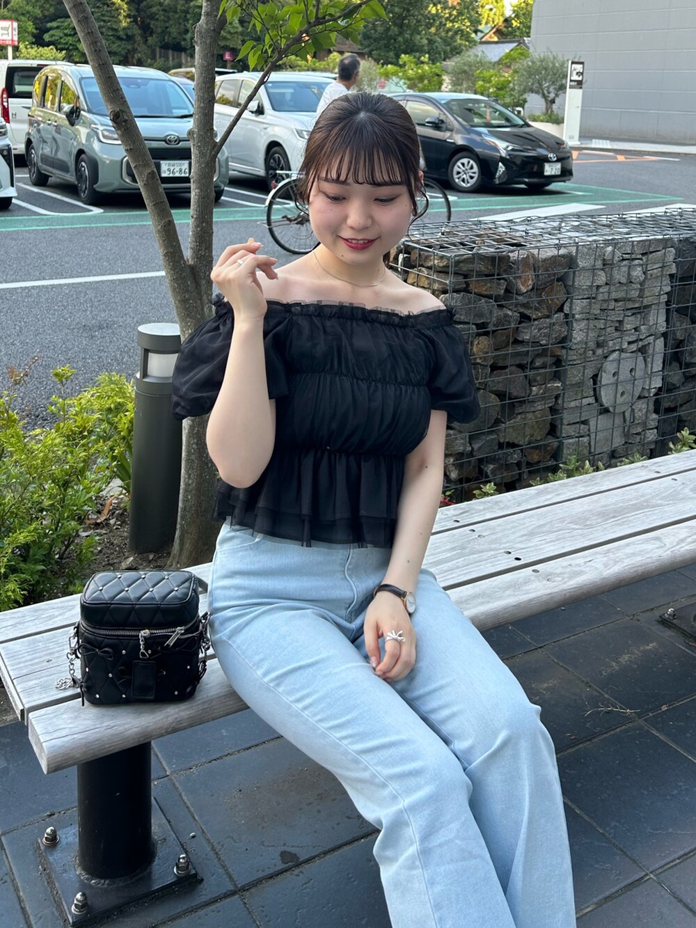 ホワイト系のショルダーバッグ、ブルー系のデニムパンツ、ブラック系のシャツ/ブラウスを着用したレディースの夏コーディネートの2枚目の写真