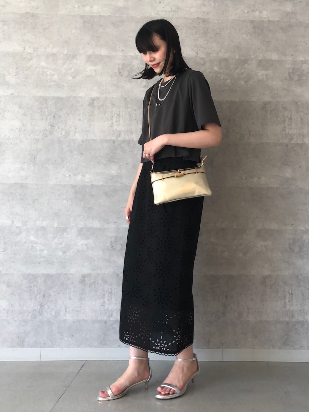 グレー系のTシャツ/カットソー、ゴールド系のショルダーバッグ、ブラック系のスカートを着用したレディースの夏コーディネートの2枚目の写真
