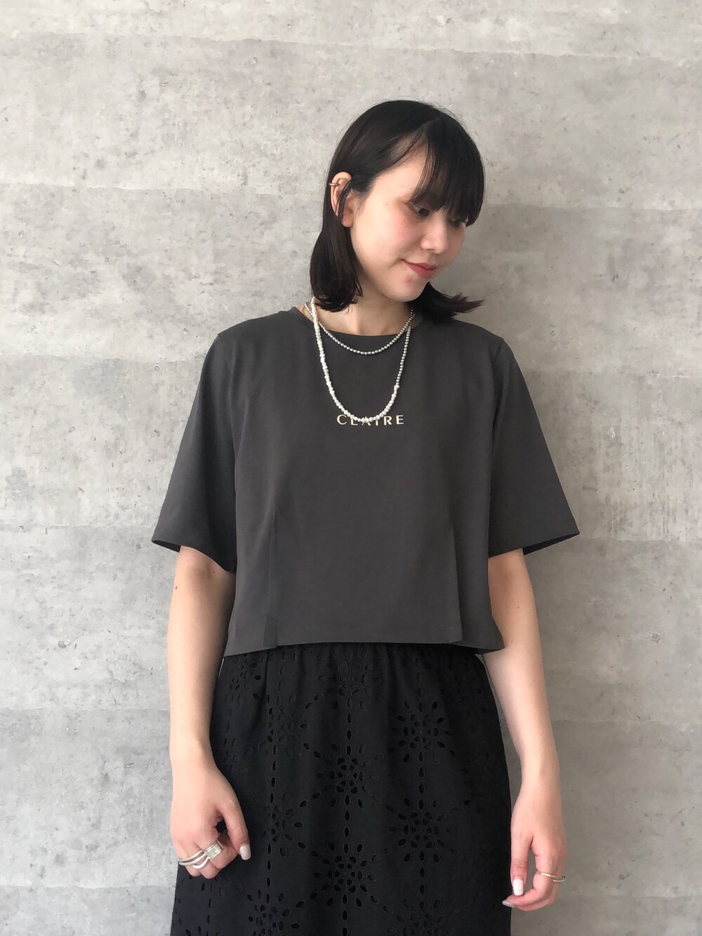 グレー系のTシャツ/カットソー、ゴールド系のショルダーバッグ、ブラック系のスカートを着用したレディースの夏コーディネートの4枚目の写真