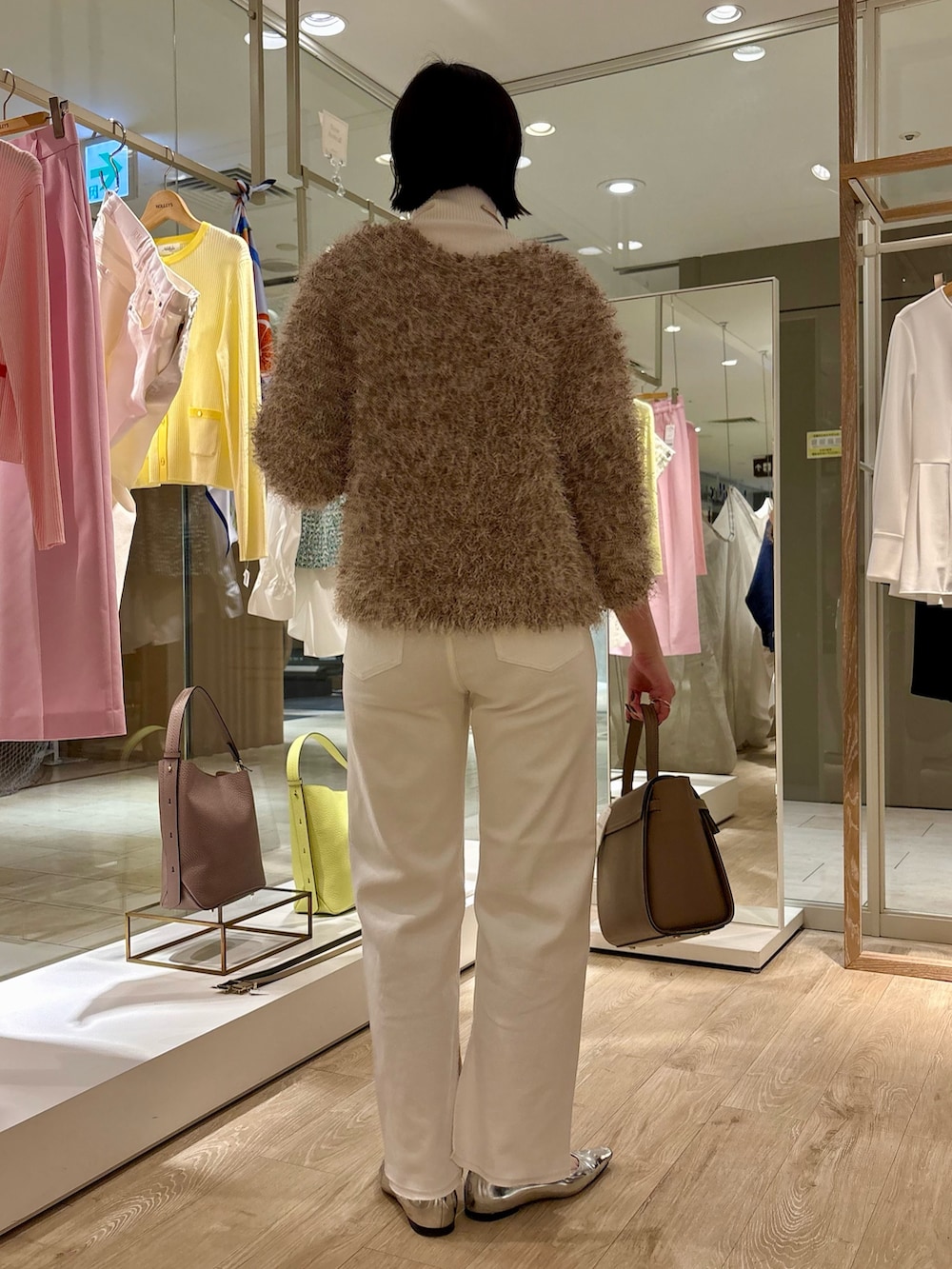 ホワイト系のニット/セーター、ベージュ系のカーディガン/ボレロ、ホワイト系のデニムパンツを着用したレディースの冬コーディネートの4枚目の写真
