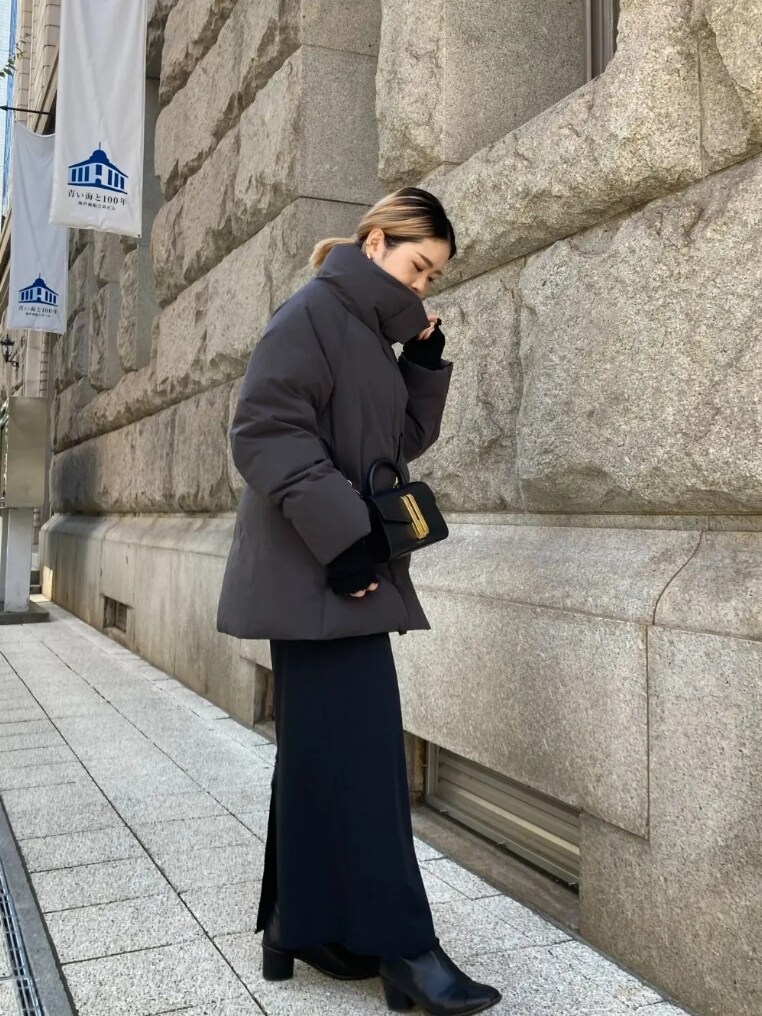 グレー系のダウンジャケット/コート、ブラック系のスカート、ブラック系のハンドバッグを着用したレディースの冬コーディネートの4枚目の写真
