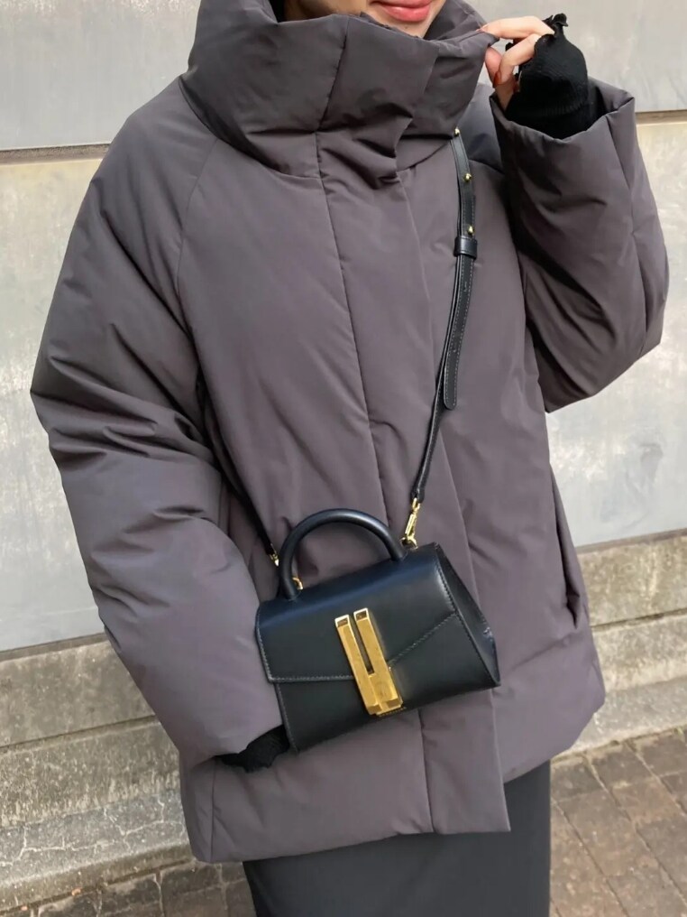 グレー系のダウンジャケット/コート、ブラック系のスカート、ブラック系のハンドバッグを着用したレディースの冬コーディネートの2枚目の写真