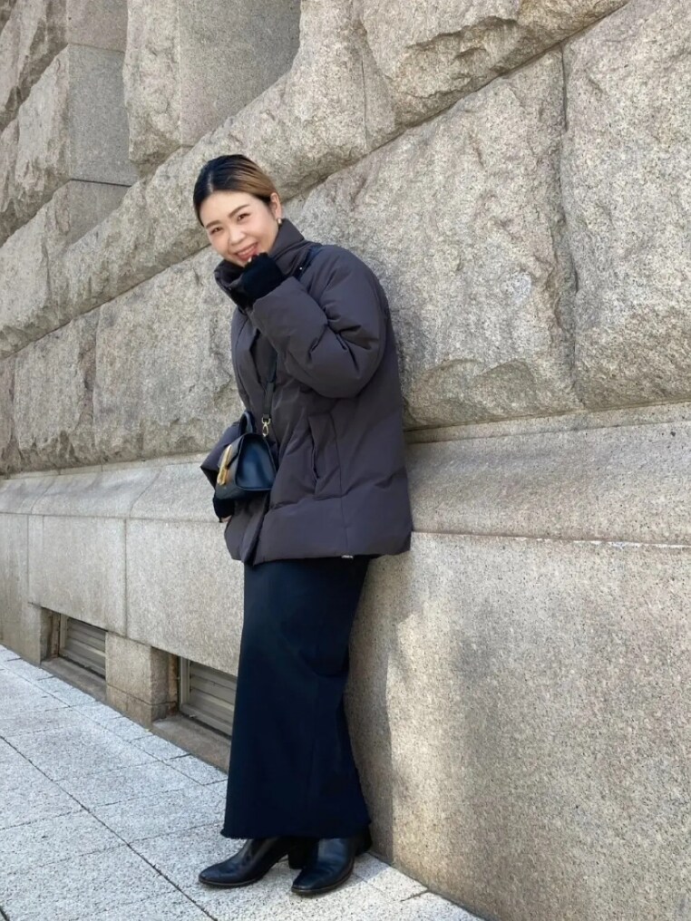 グレー系のダウンジャケット/コート、ブラック系のスカート、ブラック系のハンドバッグを着用したレディースの冬コーディネートの3枚目の写真