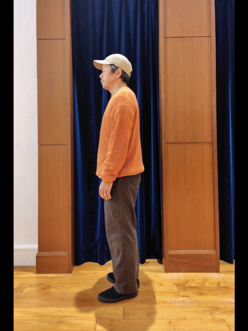 オレンジ系のニット/セーター、ベージュ系のキャップを着用したメンズの秋コーディネートの4枚目の写真