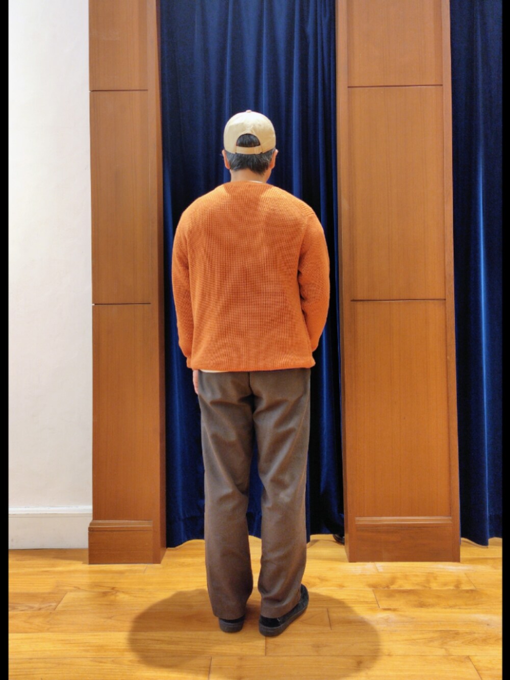 オレンジ系のニット/セーター、ベージュ系のキャップを着用したメンズの秋コーディネートの6枚目の写真