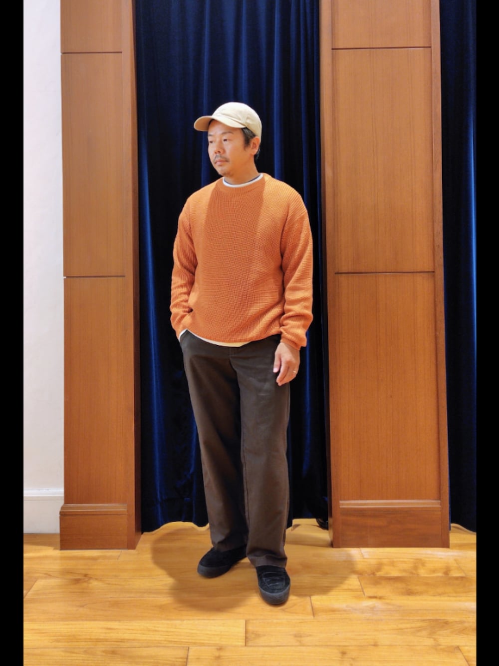 オレンジ系のニット/セーター、ベージュ系のキャップを着用したメンズの秋コーディネートの3枚目の写真