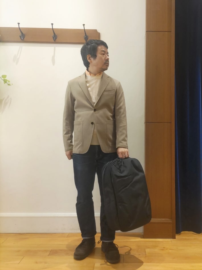 ベージュ系のテーラードジャケット、ブラック系のバックパック/リュックを着用したメンズの春コーディネートの3枚目の写真
