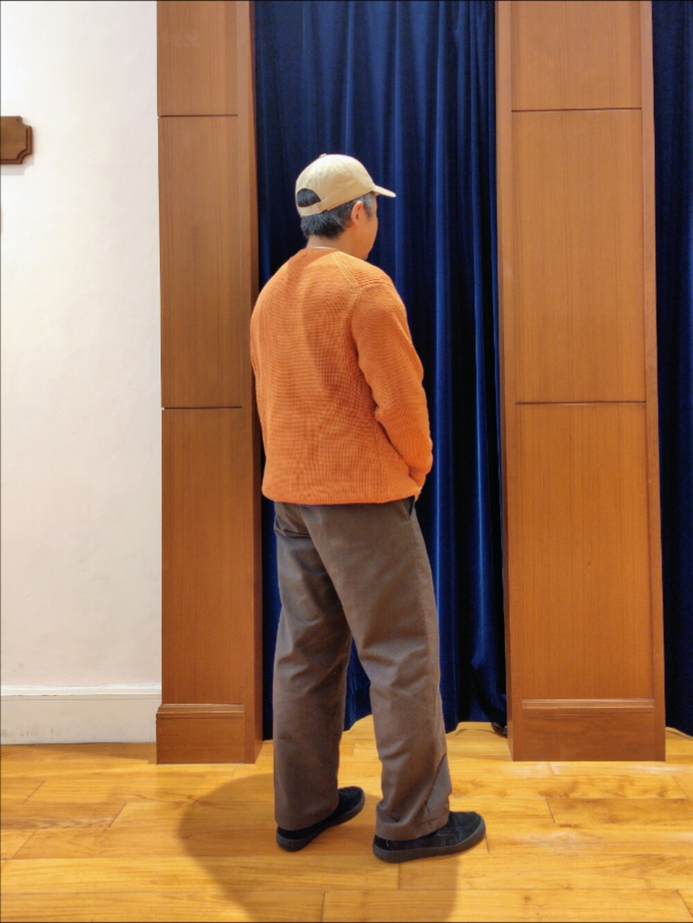 オレンジ系のニット/セーター、ベージュ系のキャップを着用したメンズの秋コーディネートの5枚目の写真