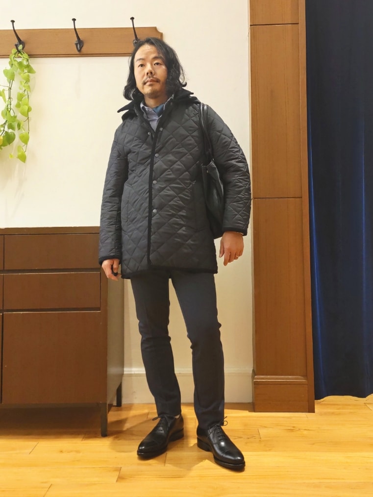 ブルー系のステンカラーコート、ブラック系のトートバッグ、ブラック系のドレスシューズを着用したメンズの秋コーディネートの4枚目の写真