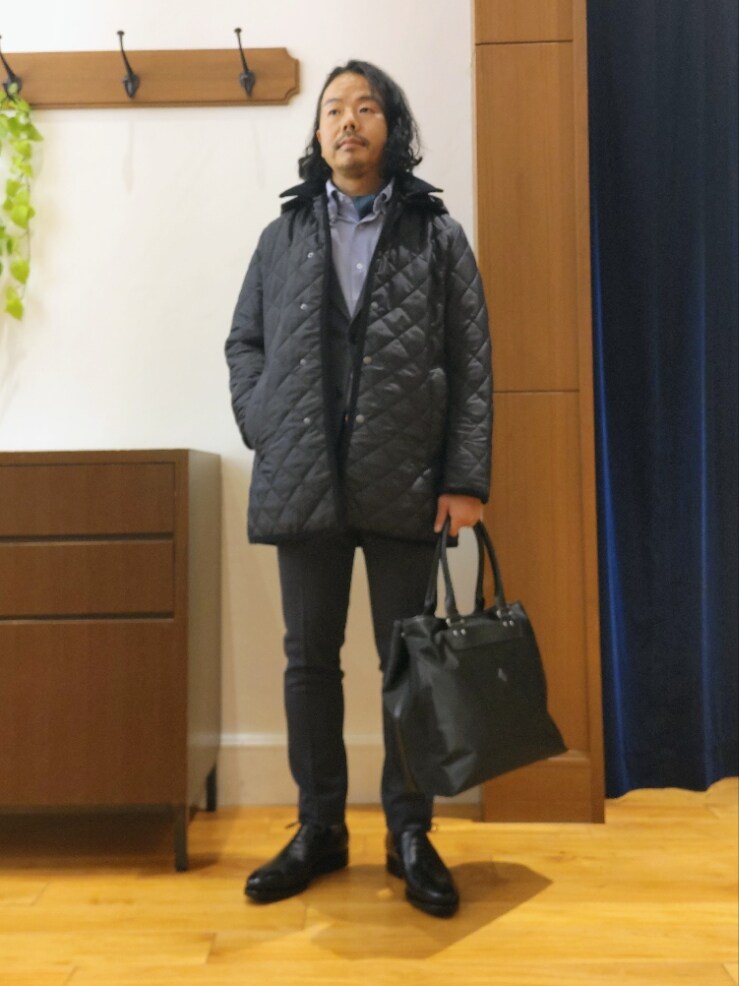 ブルー系のステンカラーコート、ブラック系のトートバッグ、ブラック系のドレスシューズを着用したメンズの秋コーディネートの2枚目の写真