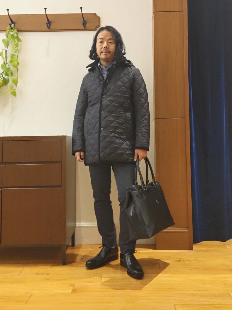 ブルー系のステンカラーコート、ブラック系のトートバッグ、ブラック系のドレスシューズを着用したメンズの秋コーディネートの3枚目の写真