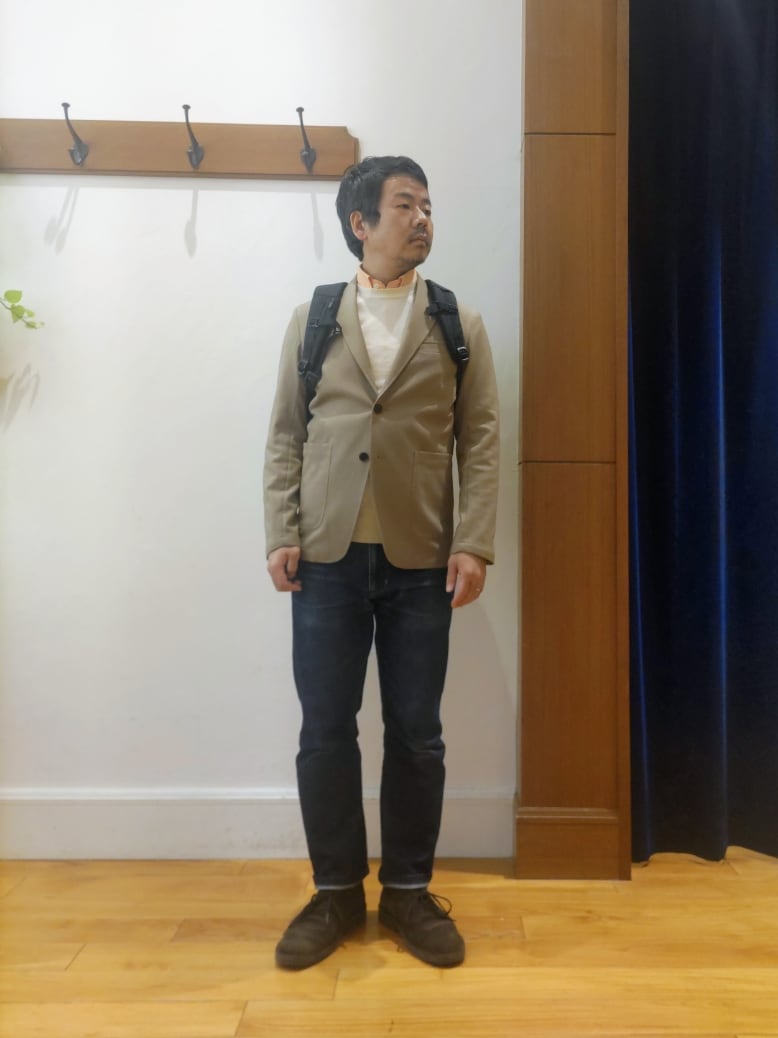 ベージュ系のテーラードジャケット、ブラック系のバックパック/リュックを着用したメンズの春コーディネートの2枚目の写真