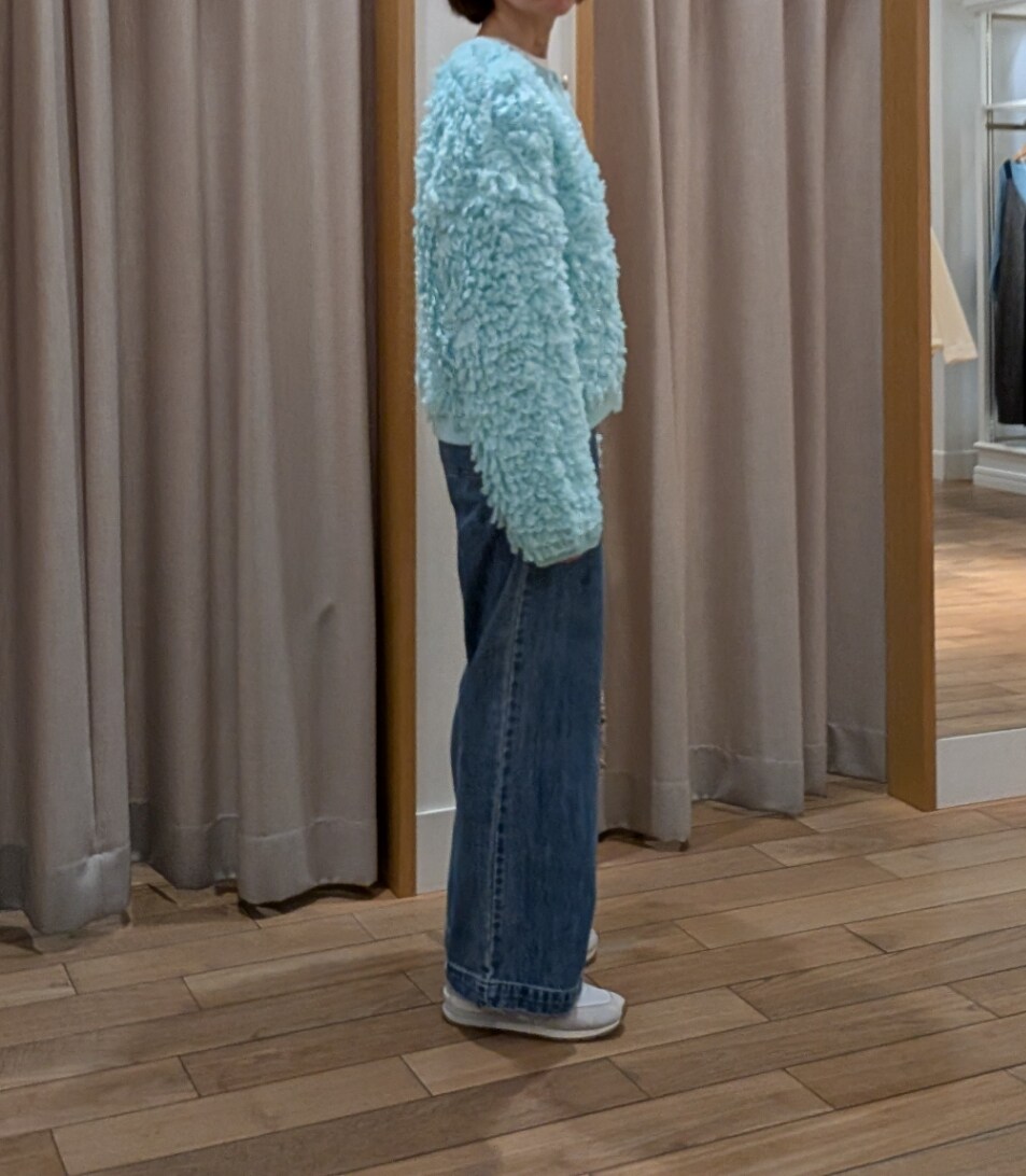 シルバー系のハンドバッグ、グリーン系のカーディガン/ボレロ、ブルー系のデニムパンツを着用したレディースの冬コーディネートの2枚目の写真