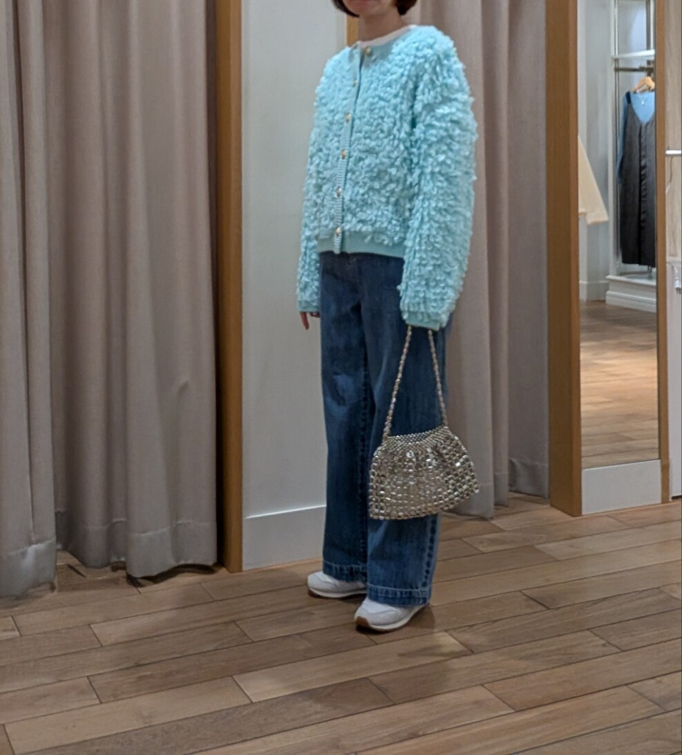 シルバー系のハンドバッグ、グリーン系のカーディガン/ボレロ、ブルー系のデニムパンツを着用したレディースの冬コーディネートの4枚目の写真