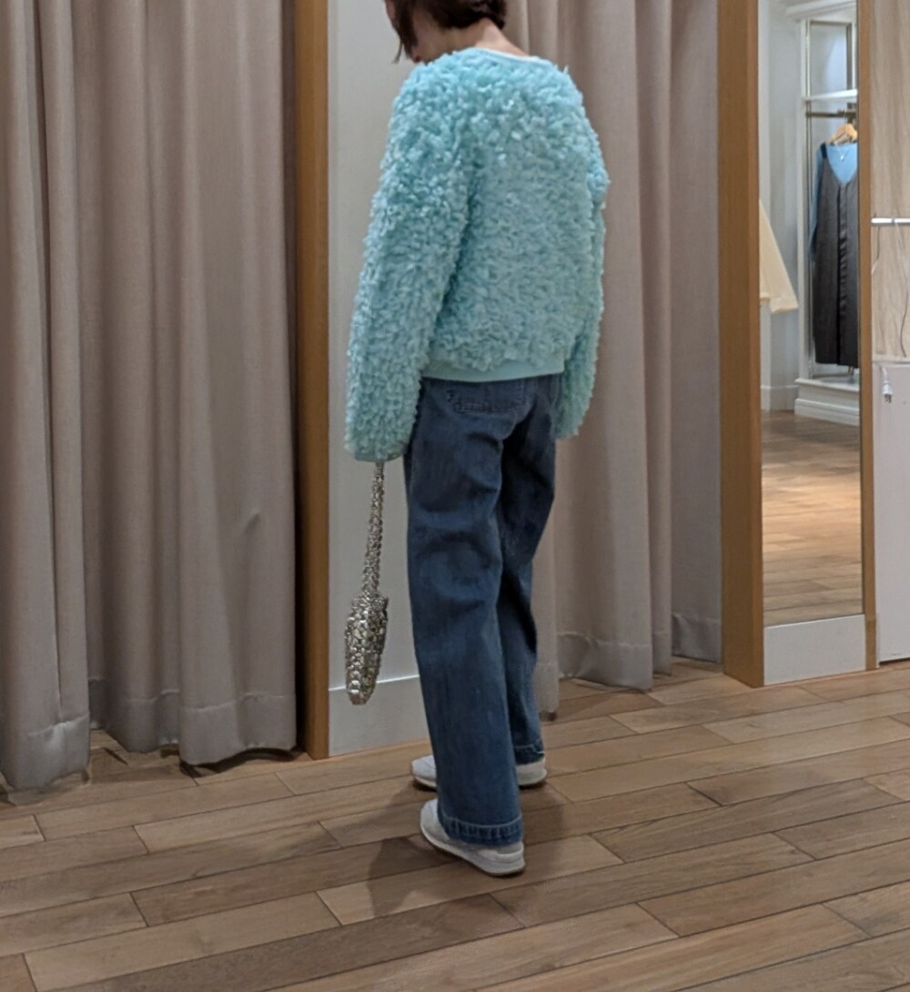 シルバー系のハンドバッグ、グリーン系のカーディガン/ボレロ、ブルー系のデニムパンツを着用したレディースの冬コーディネートの3枚目の写真