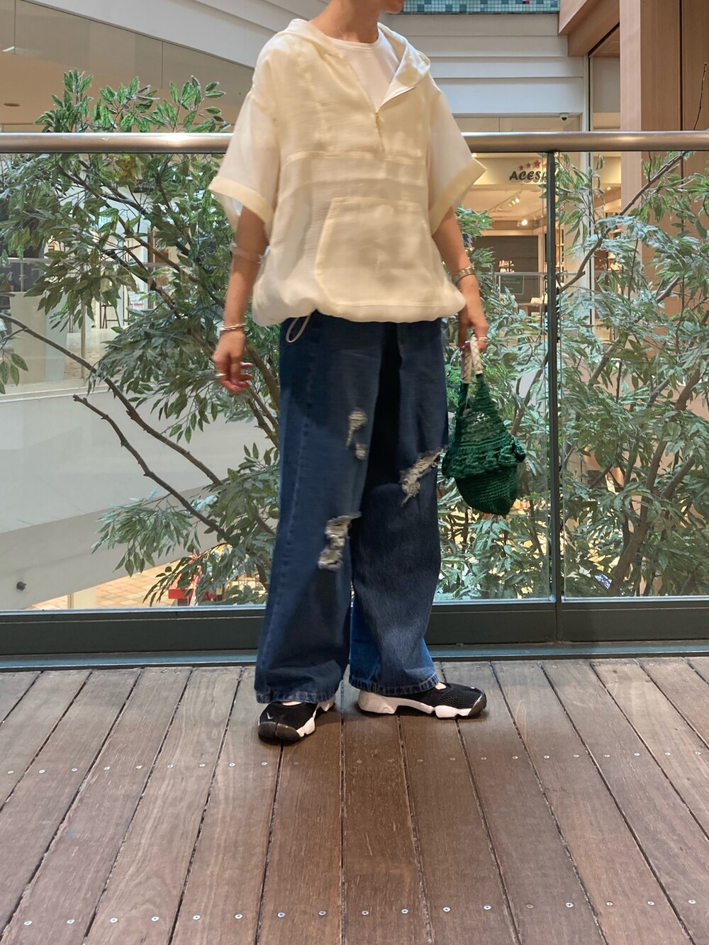 ホワイト系のブルゾン、ブルー系のデニムパンツ、グリーン系のかごバッグを着用したレディースの夏コーディネートの2枚目の写真