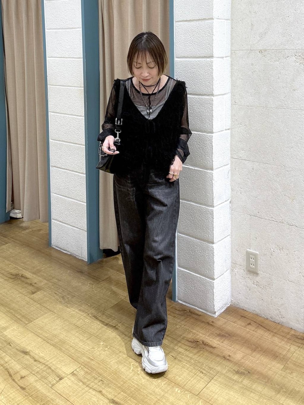 ブラック系のTシャツ/カットソー、ブラック系のデニムパンツ、シルバー系のスニーカーを着用したレディースの冬コーディネートの6枚目の写真