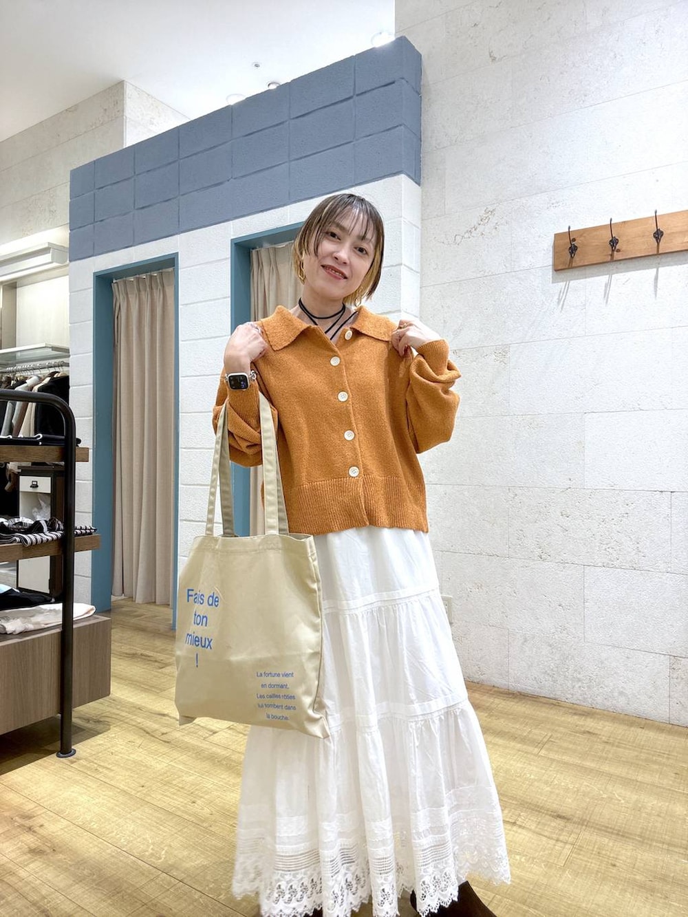 ベージュ系のトートバッグ、ブラウン系のサンダル、オレンジ系のカーディガン/ボレロを着用したレディースの春コーディネートの6枚目の写真