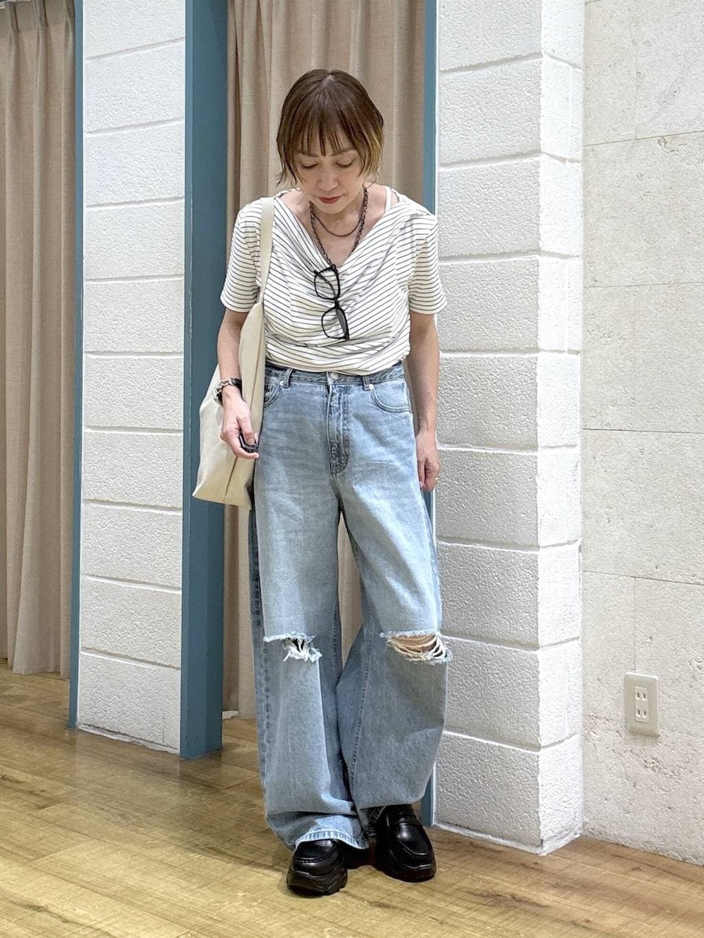 ブルー系のデニムパンツ、ブラック系のローファー、ホワイト系のショルダーバッグを着用したレディースの春コーディネートの2枚目の写真