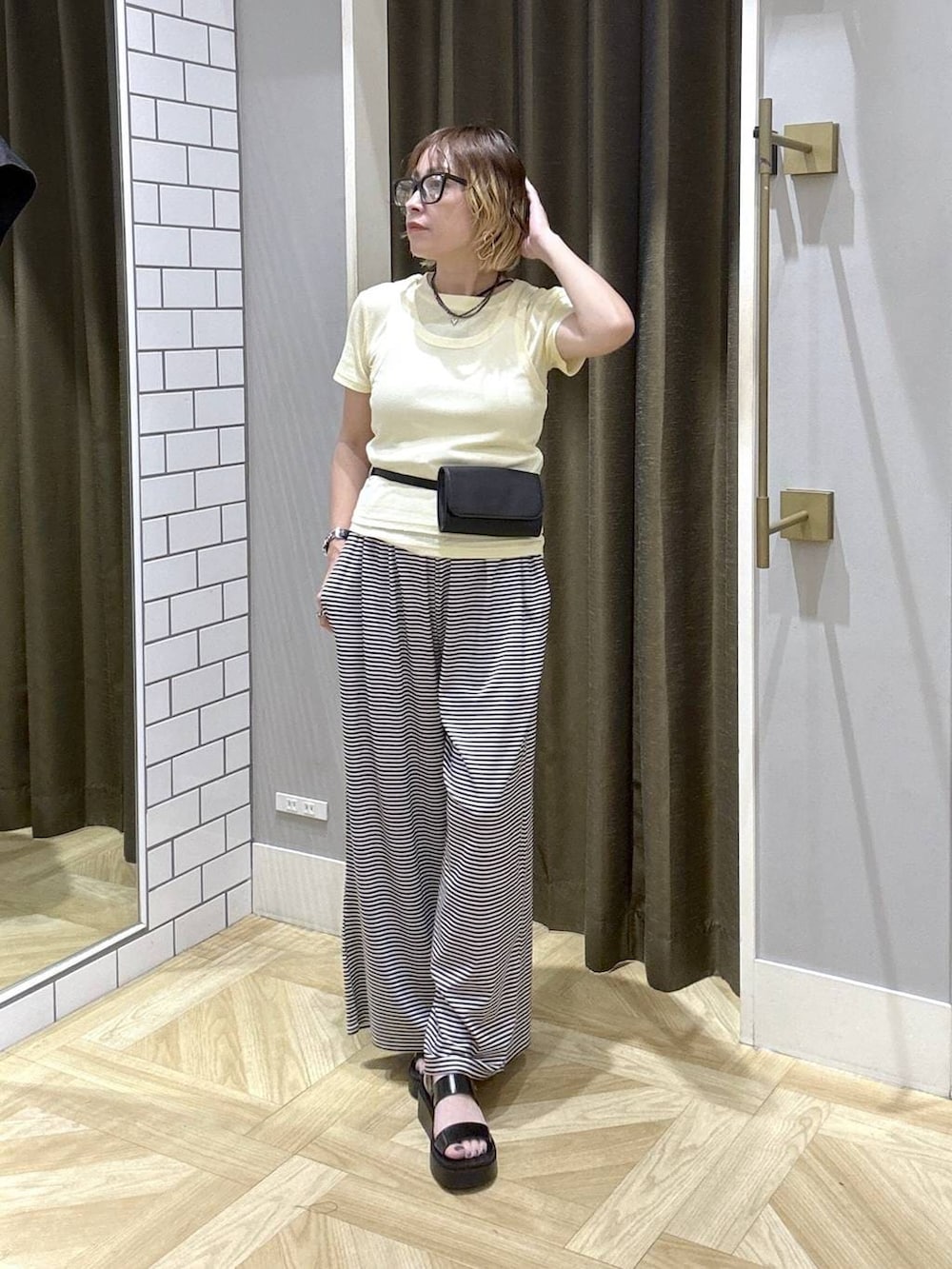 イエロー系のTシャツ/カットソー、ホワイト系のその他パンツ、ブラック系のサンダルを着用したレディースの夏コーディネートの2枚目の写真