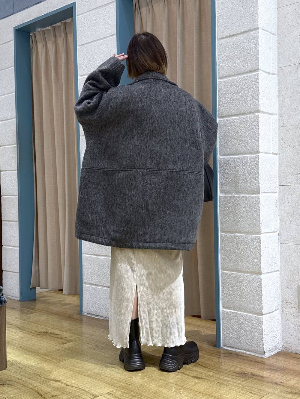 ブラック系のブーツ、グレー系のその他アウター、ブラック系のショルダーバッグを着用したレディースの秋コーディネートの3枚目の写真