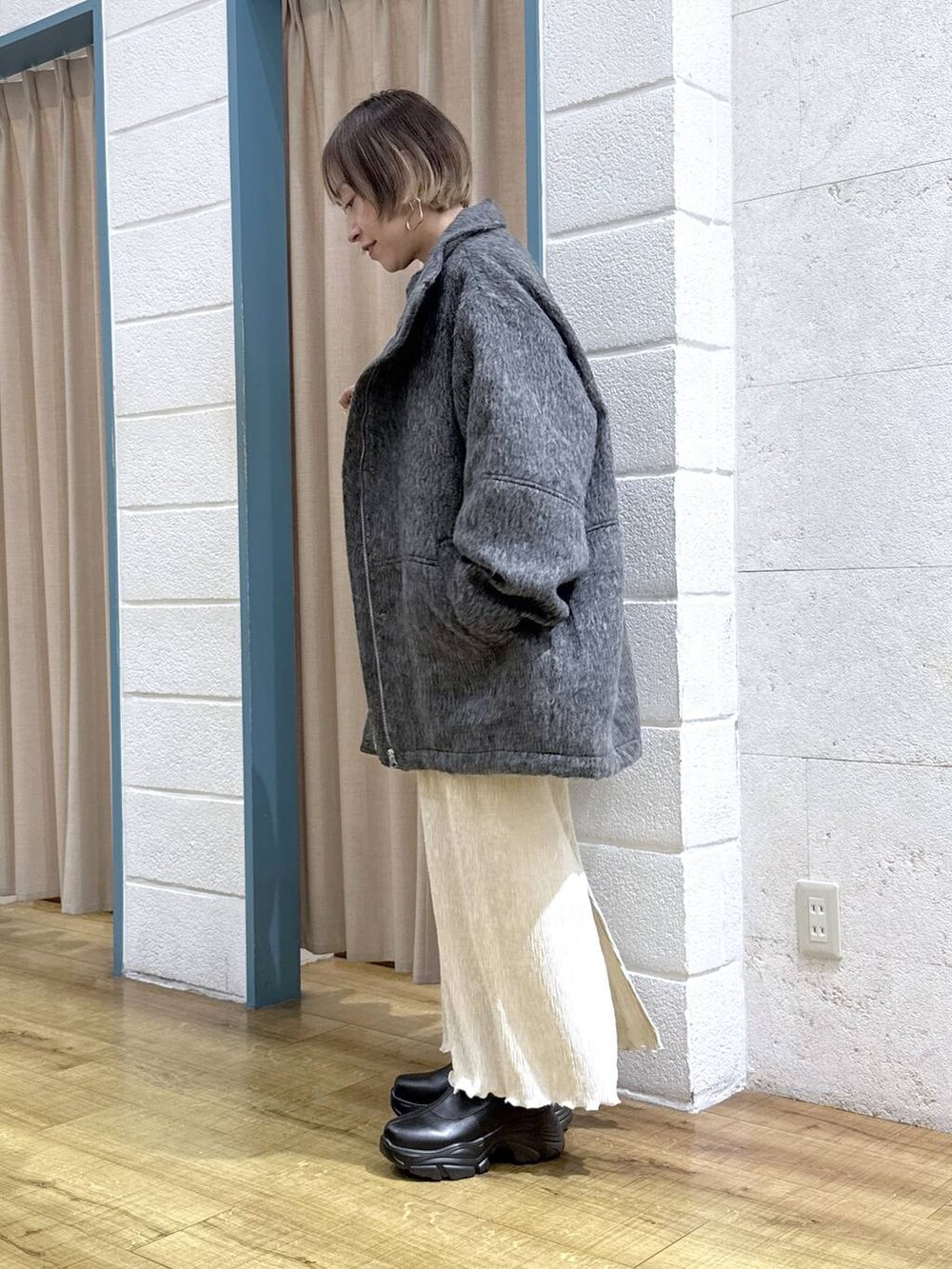 ブラック系のブーツ、グレー系のその他アウター、ブラック系のショルダーバッグを着用したレディースの秋コーディネートの2枚目の写真