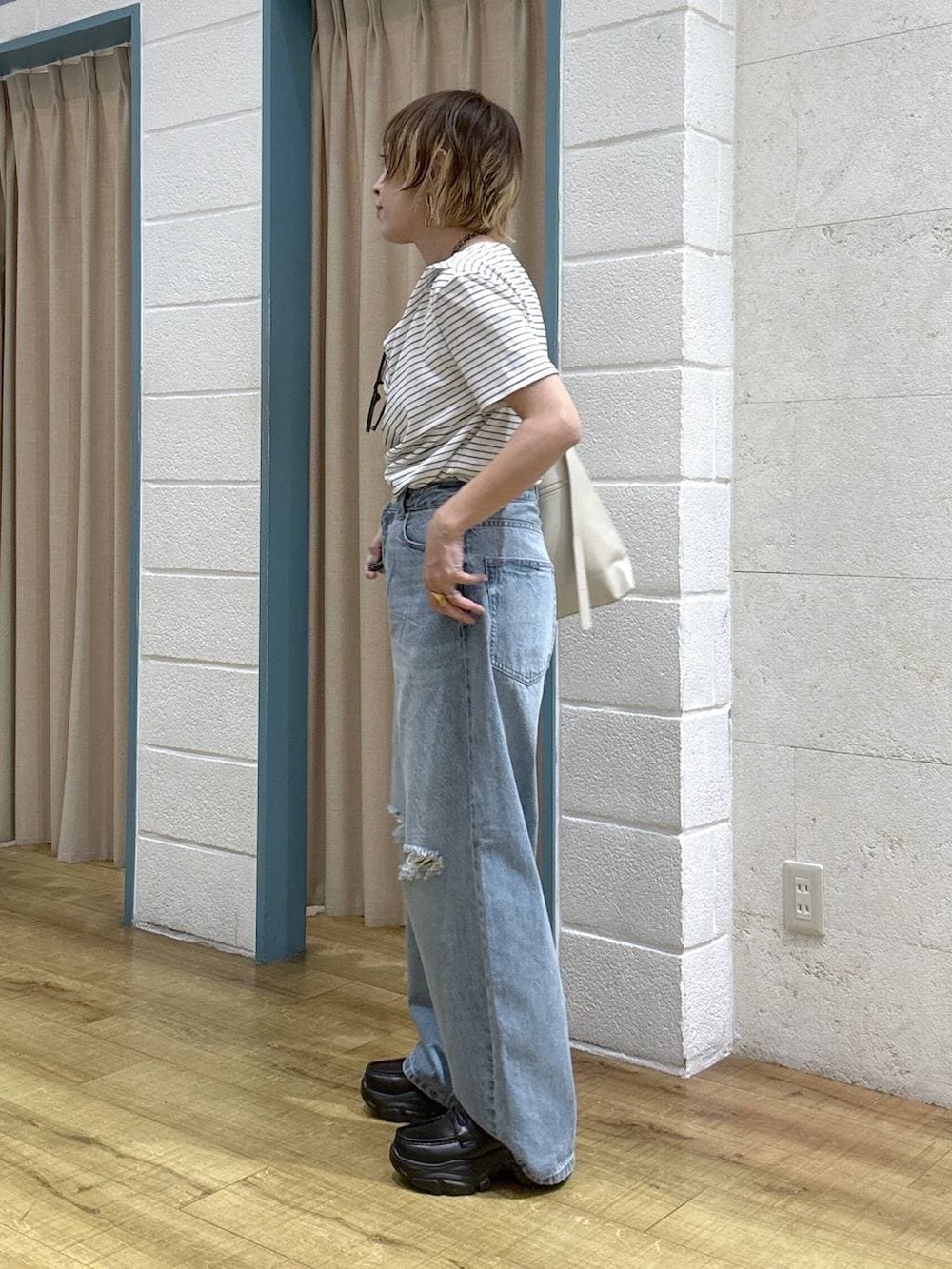ブルー系のデニムパンツ、ブラック系のローファー、ホワイト系のショルダーバッグを着用したレディースの春コーディネートの3枚目の写真