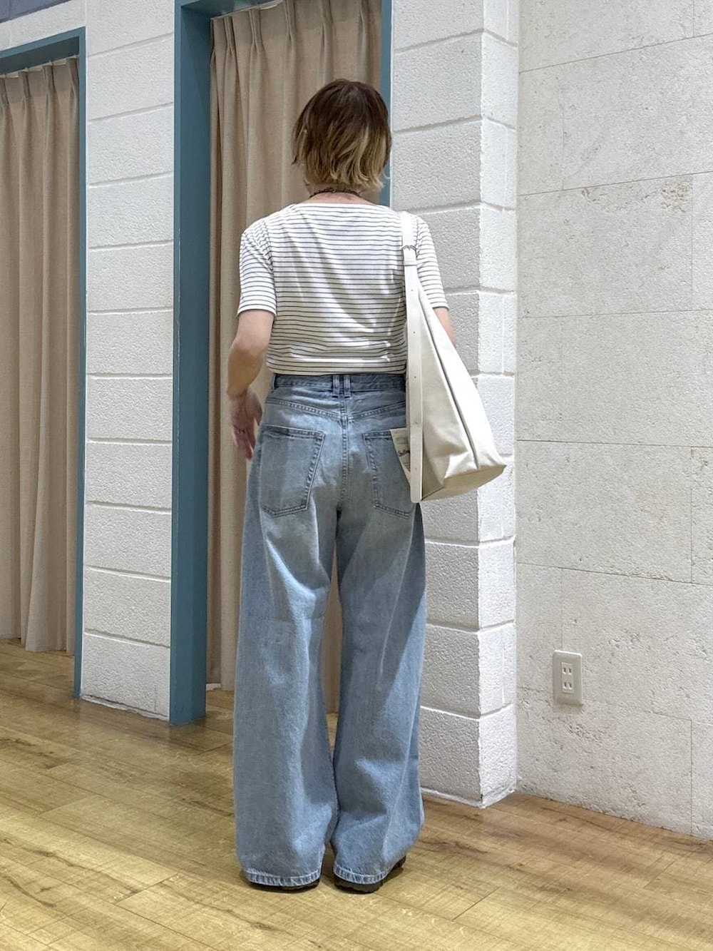 ブルー系のデニムパンツ、ブラック系のローファー、ホワイト系のショルダーバッグを着用したレディースの春コーディネートの4枚目の写真