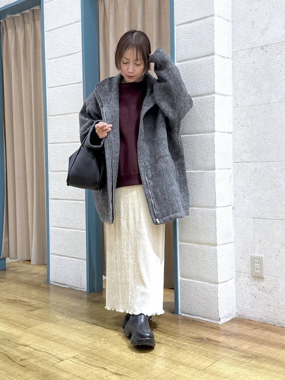 ブラック系のブーツ、グレー系のその他アウター、ブラック系のショルダーバッグを着用したレディースの秋コーディネートの5枚目の写真